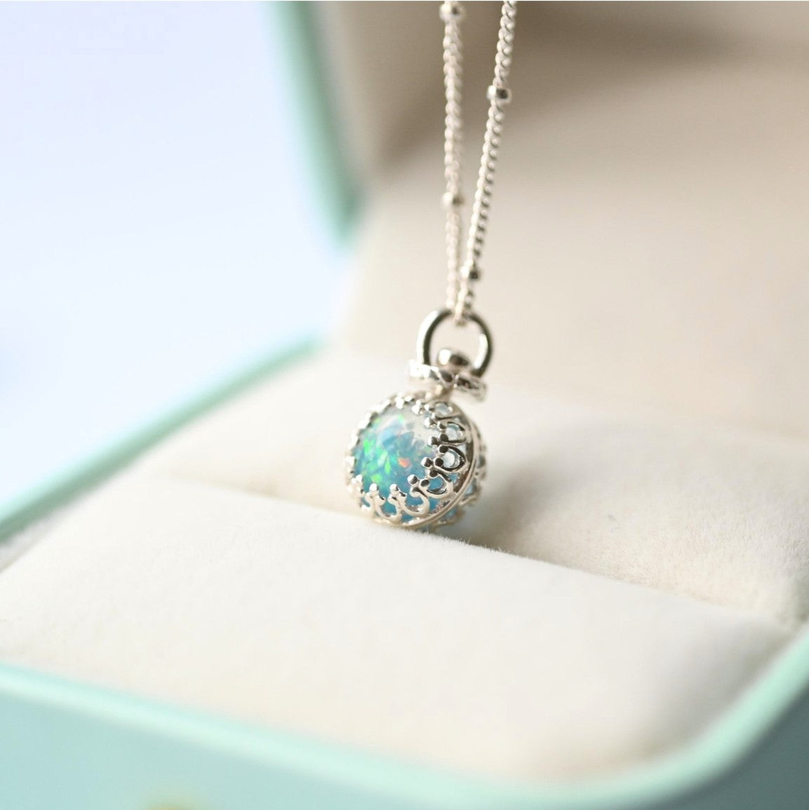 Close-up of a sterling silver 8mm ball necklace with ashes and opal flakes, set on an 18-inch chain, designed as a memorial keepsake.