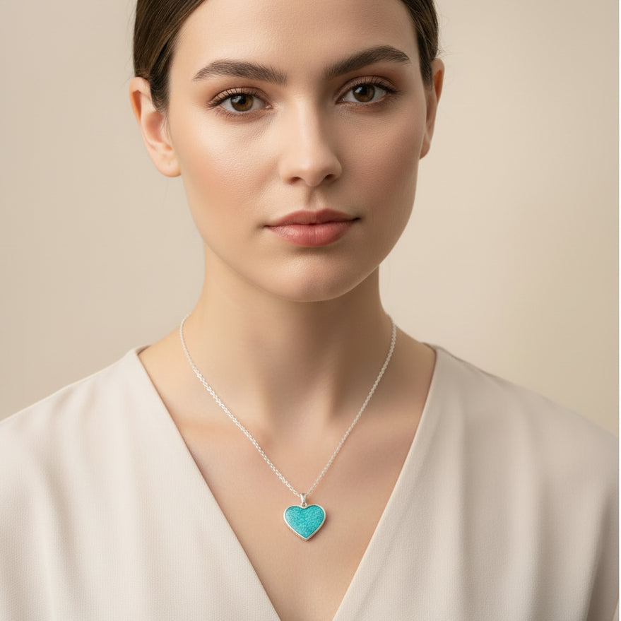 Turquoise heart-shaped pendant on a silver chain held in hand