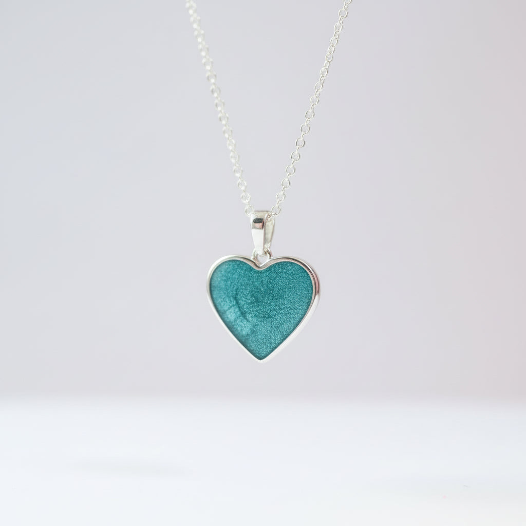 Heart-shaped turquoise pendant on a silver chain against a white background