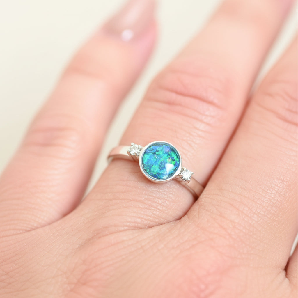 Ring with a colorful gemstone on a finger against a light background