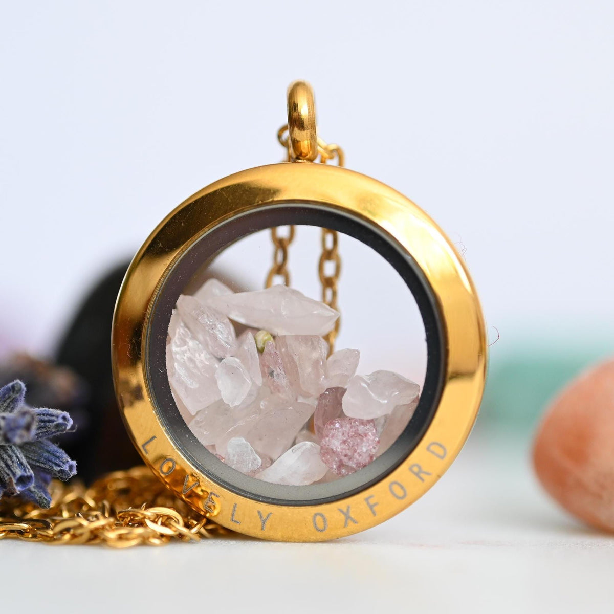 Gold locket with crystals and 'Lovely Oxford' engraving on a light background