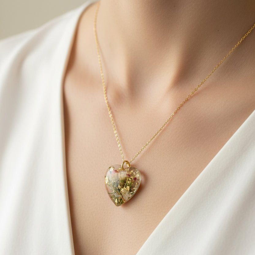 Heart-shaped pendant with floral elements on a gold chain against a floral background