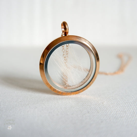 Close-up of Pet Fur Memorial Locket with Paw Print Design – A detailed view of a glass locket containing pet fur, featuring a paw print pendant, customised as a keepsake.