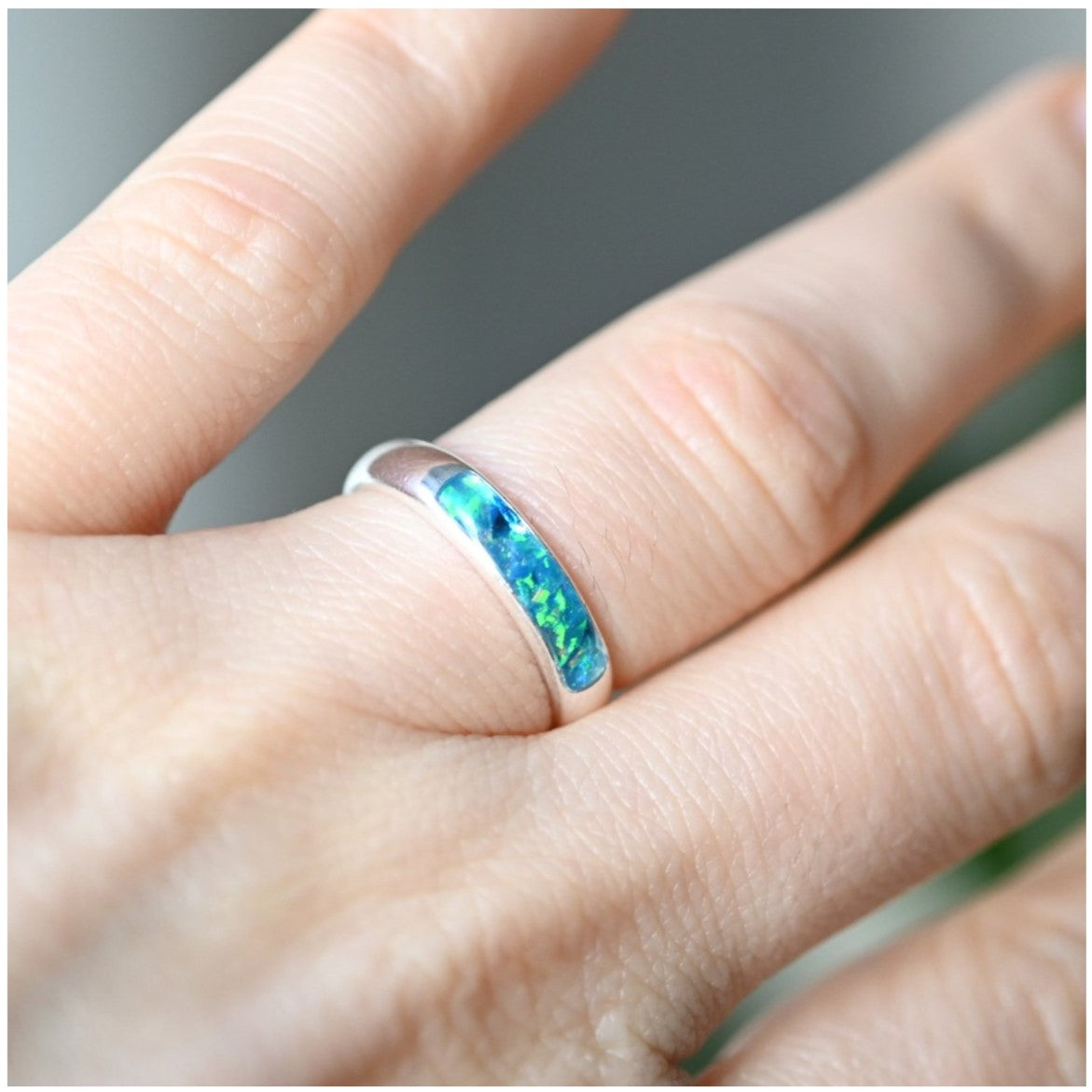 Side view of the ladies silver channel ring, highlighting the opals and memorial ashes set within the band.