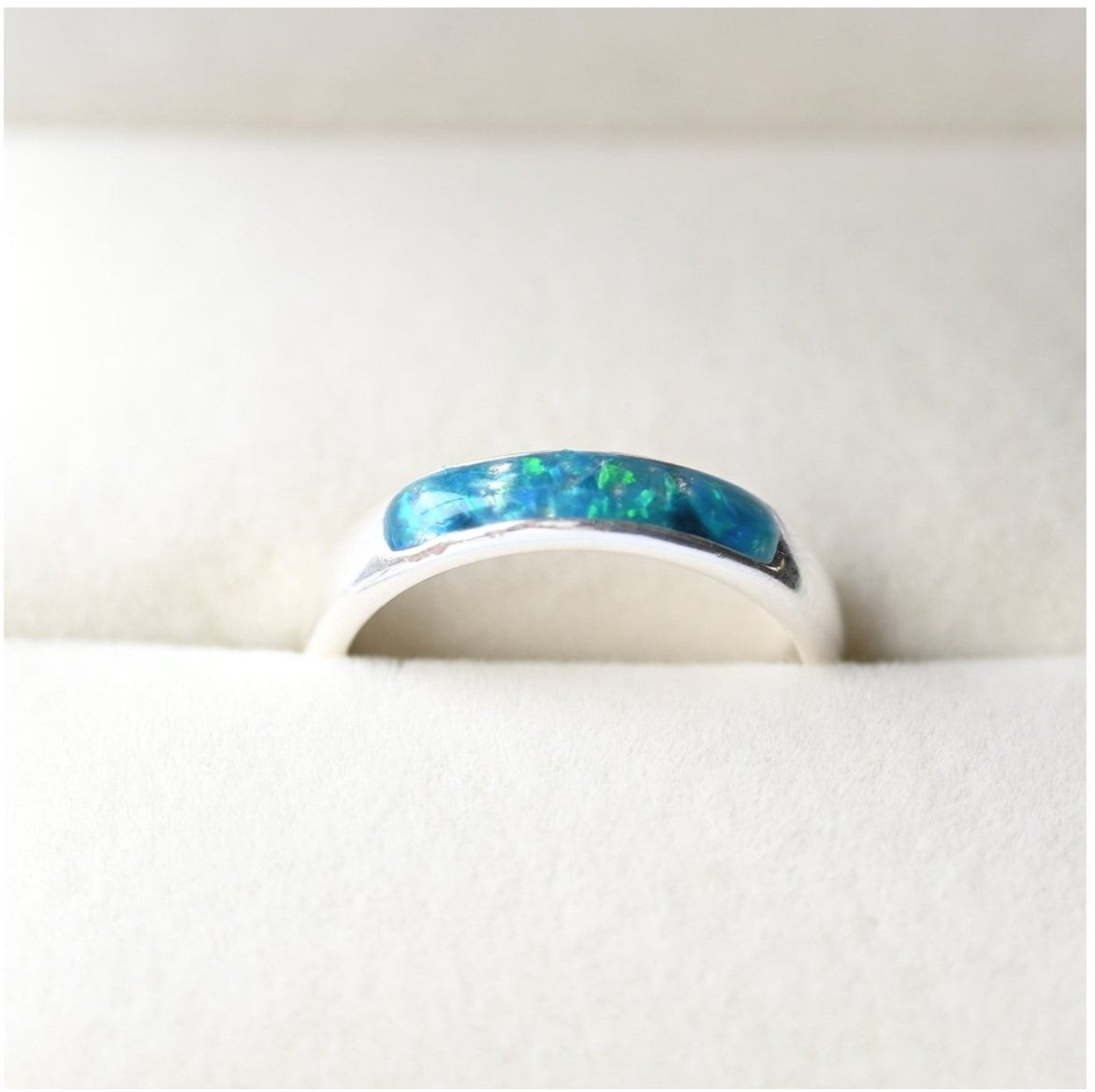 Ladies silver channel ring with opals and a small amount of memorial ashes, creating a sentimental tribute.
