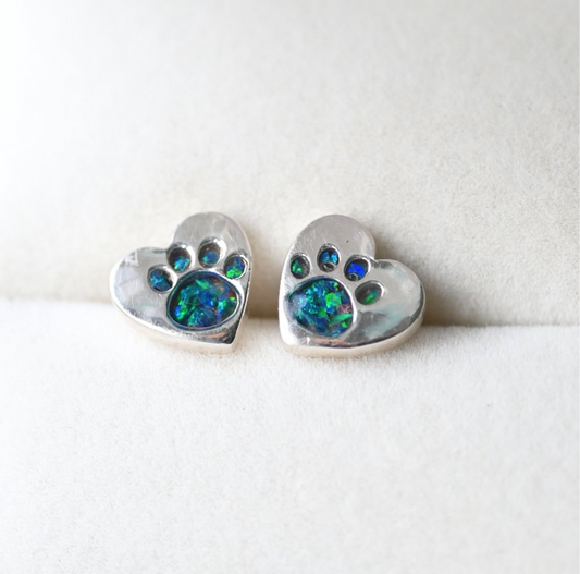 A pair of 9mm sterling silver heart-shaped stud earrings featuring delicate paw print engravings, designed as a heartfelt pet memorial keepsake.