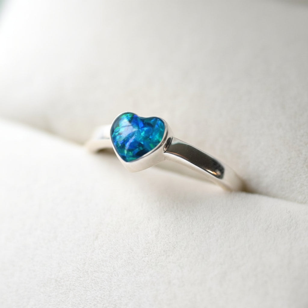 Close-up of a 6mm heart memorial ring in sterling silver, featuring ashes and opal flakes.