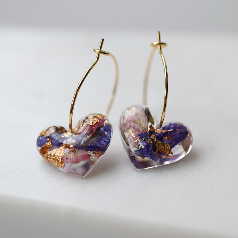 Heart-shaped earrings with gold and purple accents on a light background