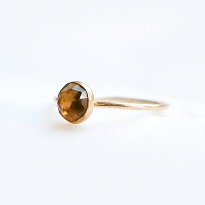 Gold ring with a faceted brown gemstone on a light background