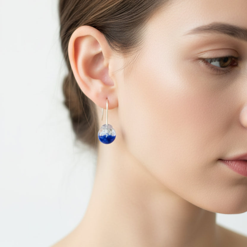 Single blue earring on a light gray background