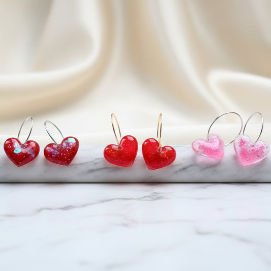 Heart-shaped earrings displayed on a wooden stick with white background