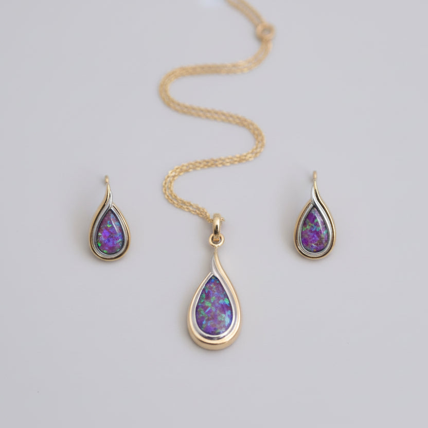 Gold necklace with teardrop-shaped purple gemstones on a light gray background