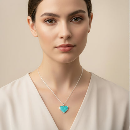 Turquoise heart-shaped pendant on a silver chain held in hand