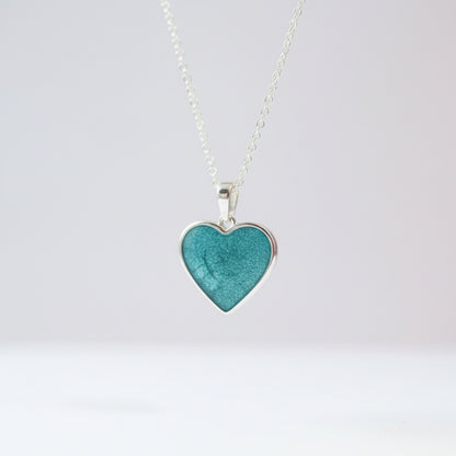 Heart-shaped turquoise pendant on a silver chain against a white background