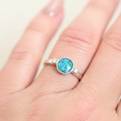 Ring with a colorful gemstone on a finger against a light background