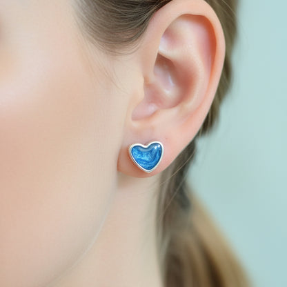 Heart-shaped blue earring worn by a person with a blurred background