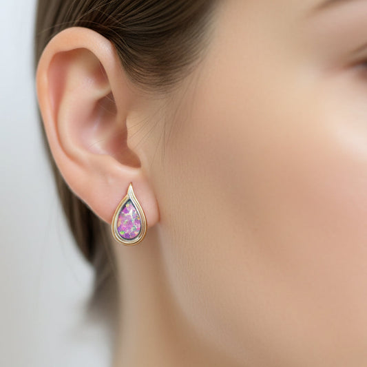 Close-up of a person wearing a pink teardrop earring with a blurred background