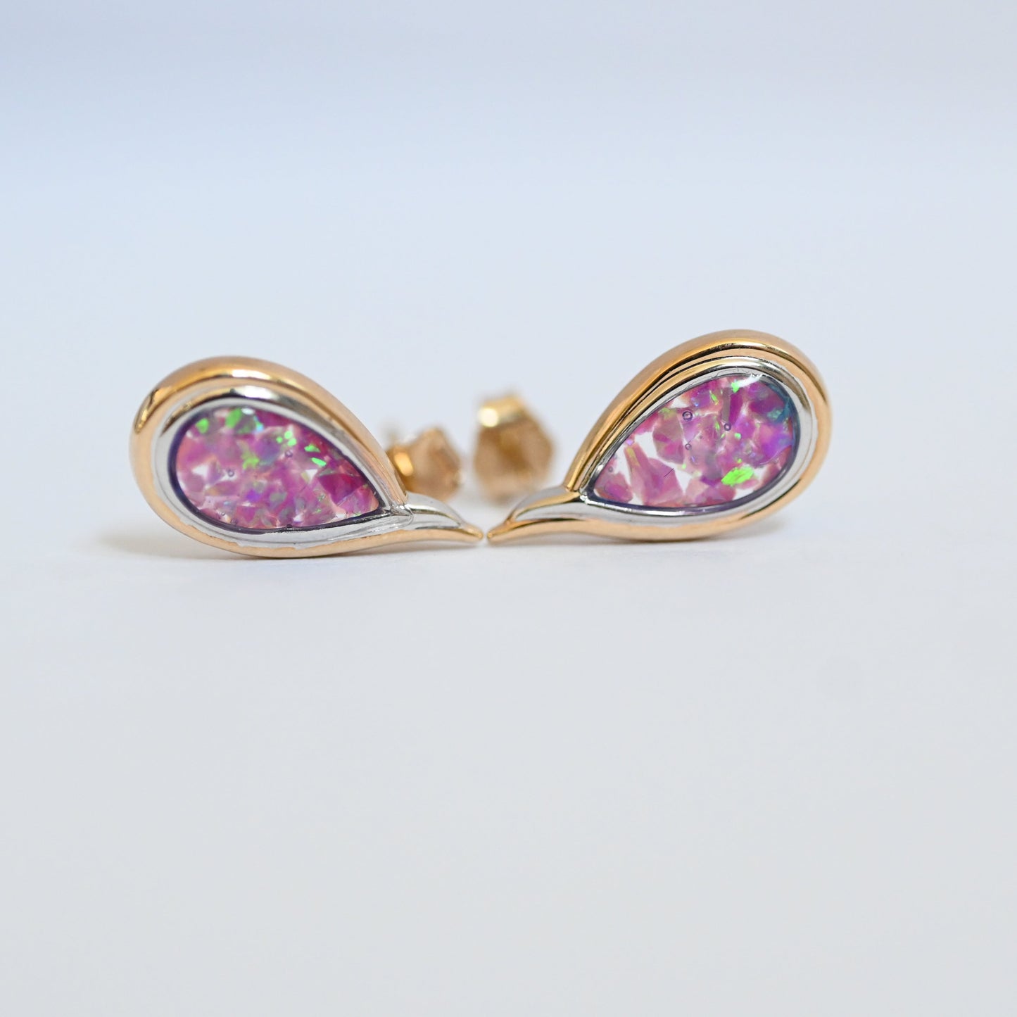 Gold teardrop earrings with pink gemstones on a light gray background
