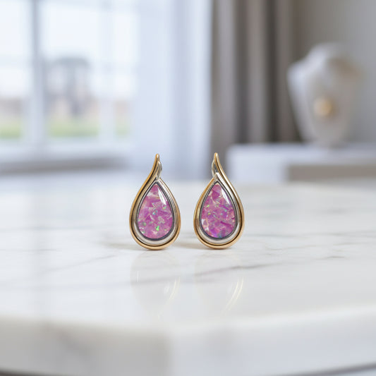 Gold teardrop earrings with pink gemstones on a light gray background