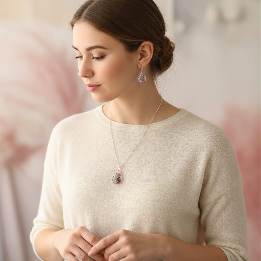 Woman wearing a necklace and earrings with a soft pink background