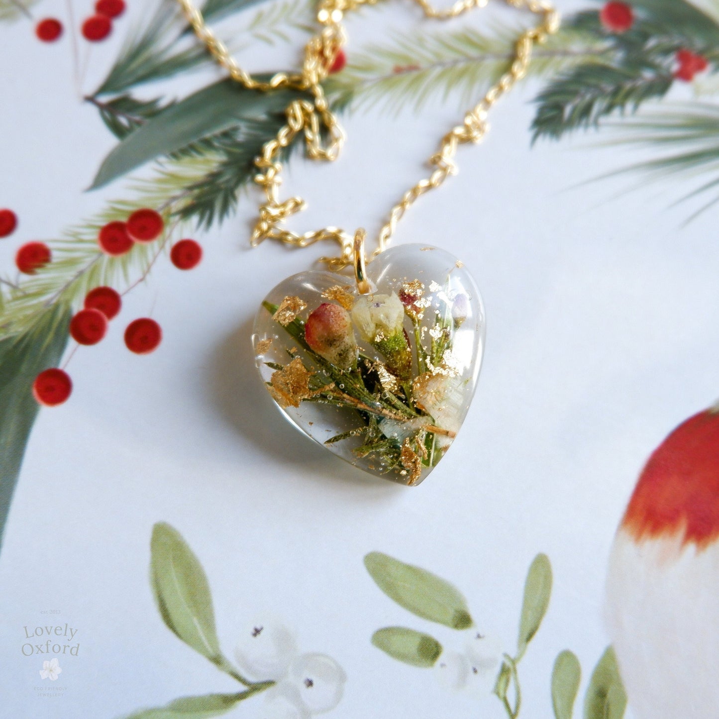 Heart-shaped pendant with floral elements on a gold chain against a floral background