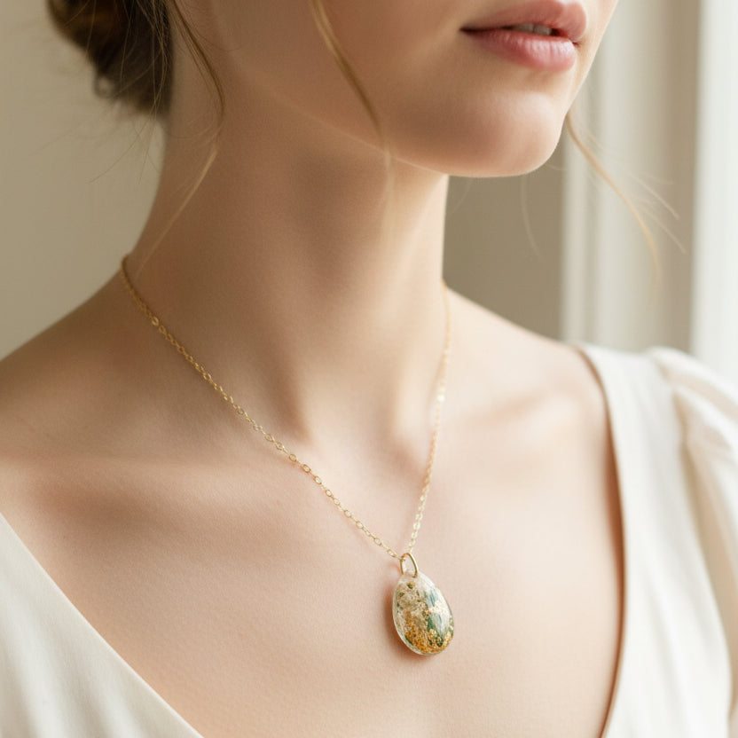 Necklace with a pendant featuring dried flowers and gold accents on a light background