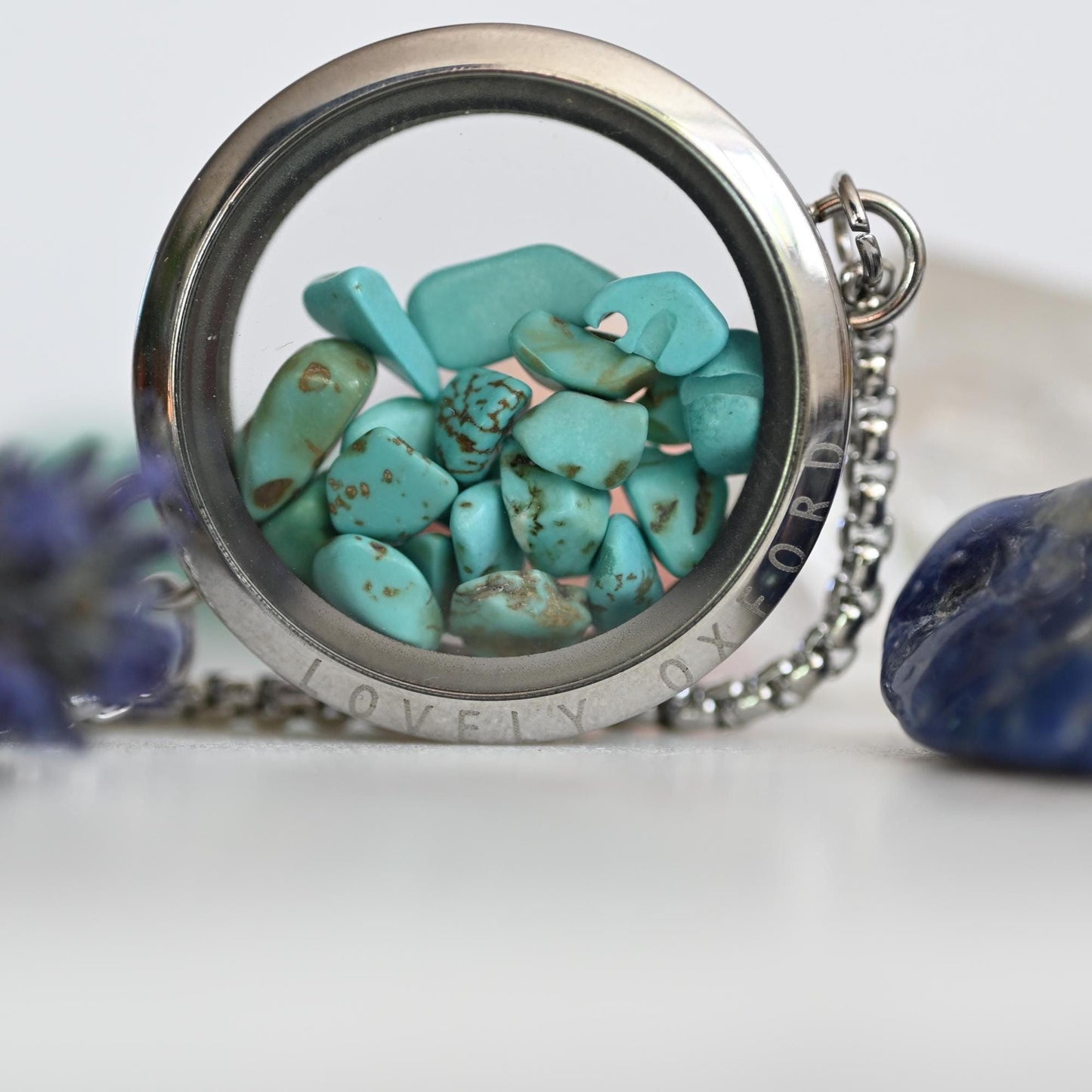 Necklace with turquoise stones inside a silver locket on a white background