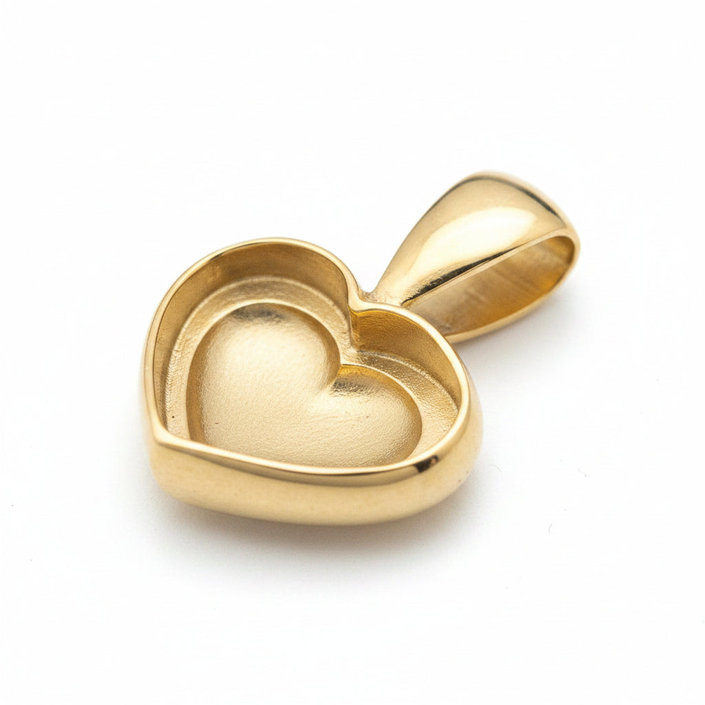 A small polished gold heart-shaped pendant with a matching bail, resting on a neutral gray surface.