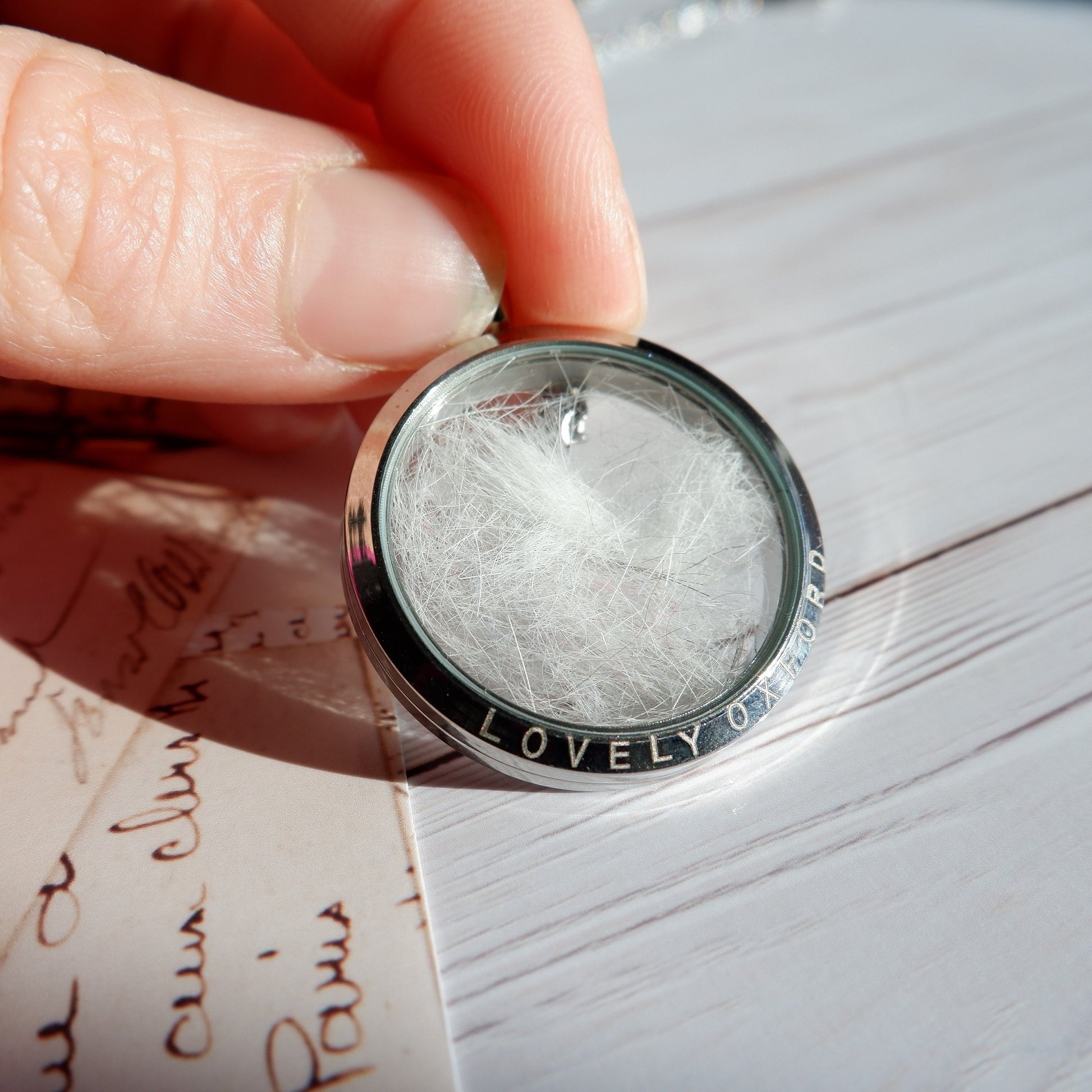 Silver ring with textured design held over a piece of paper with cursive writing.