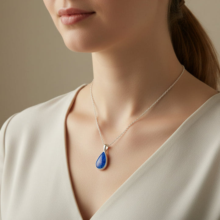 Teardrop-shaped blue pendant on a silver chain against a white background