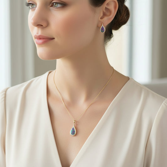 Woman wearing a gold necklace with a teardrop pendant and matching earrings.
