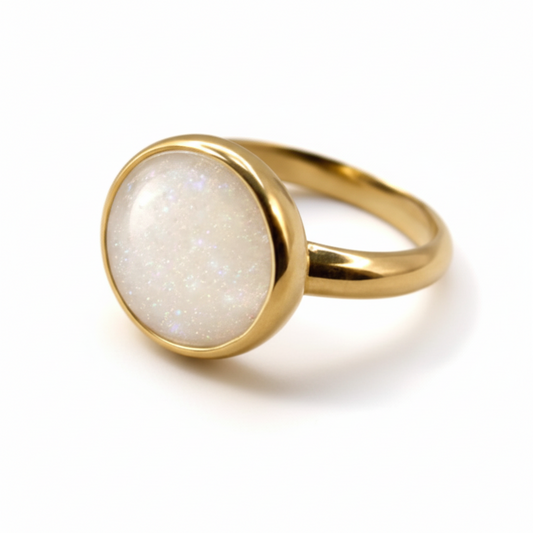 Gold ring with a white stone on a light background