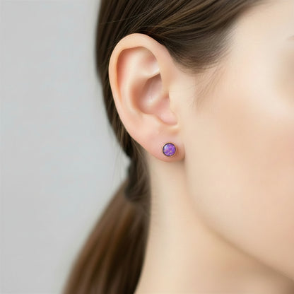 Close-up of gold-filled 4mm stud earrings with ashes and opal flakes, a delicate memorial keepsake.