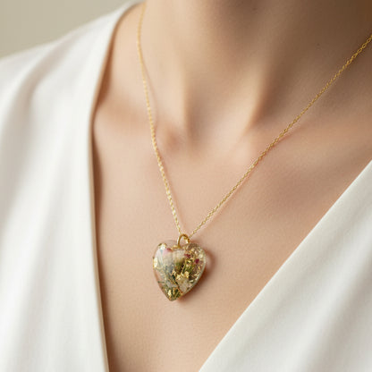 Heart-shaped pendant with floral elements on a gold chain against a floral background