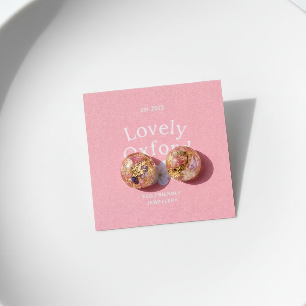 Pair of earrings on a pink card with 'Lovely Oxford' branding on a marble surface.