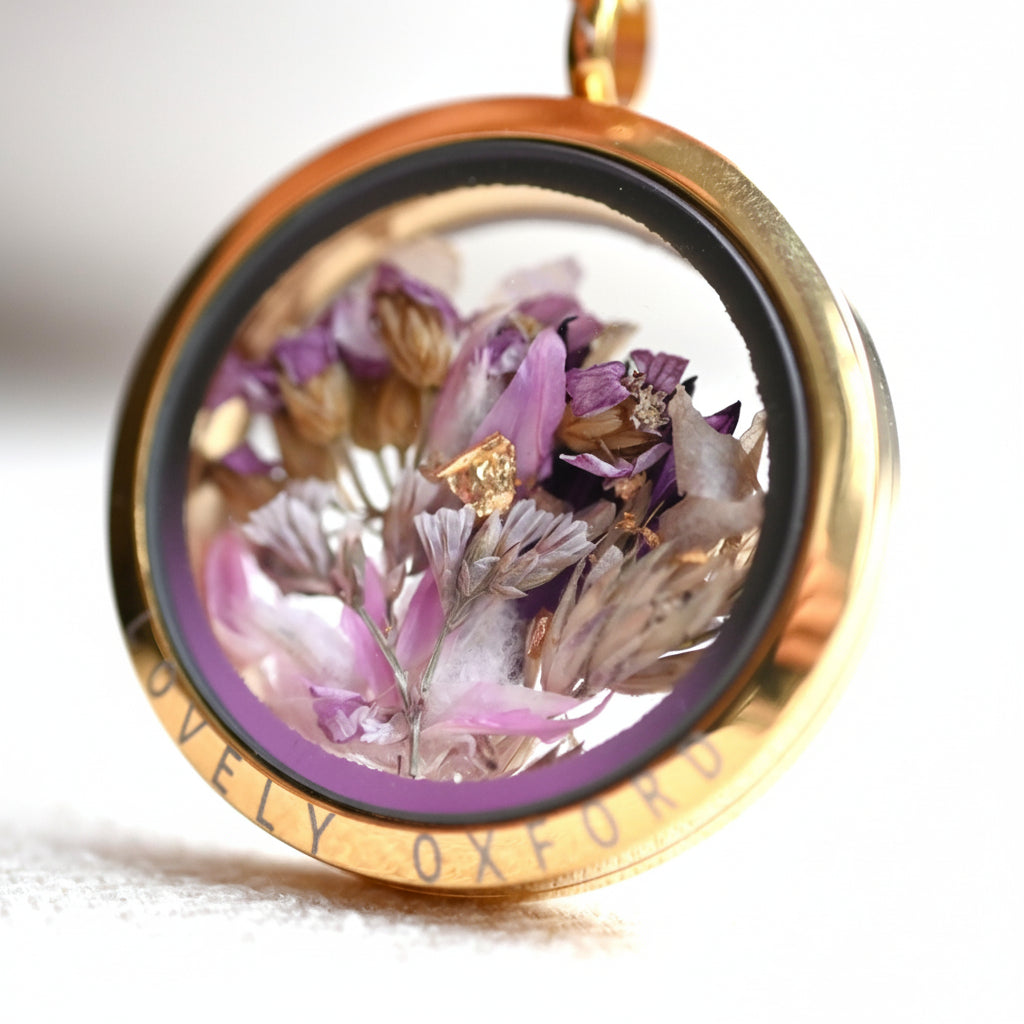 Gold pendant with dried flowers inside on a white background