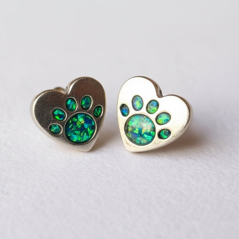 Heart-shaped earrings with opal-like stones on a light gray background