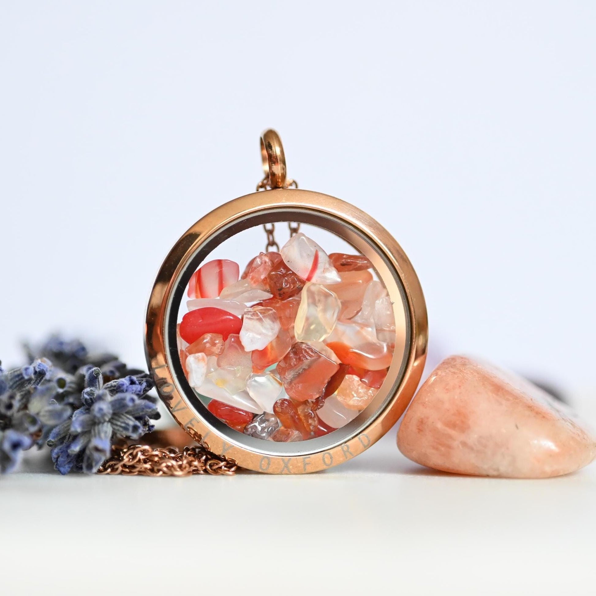Rose gold pendant with embedded stones on a light background