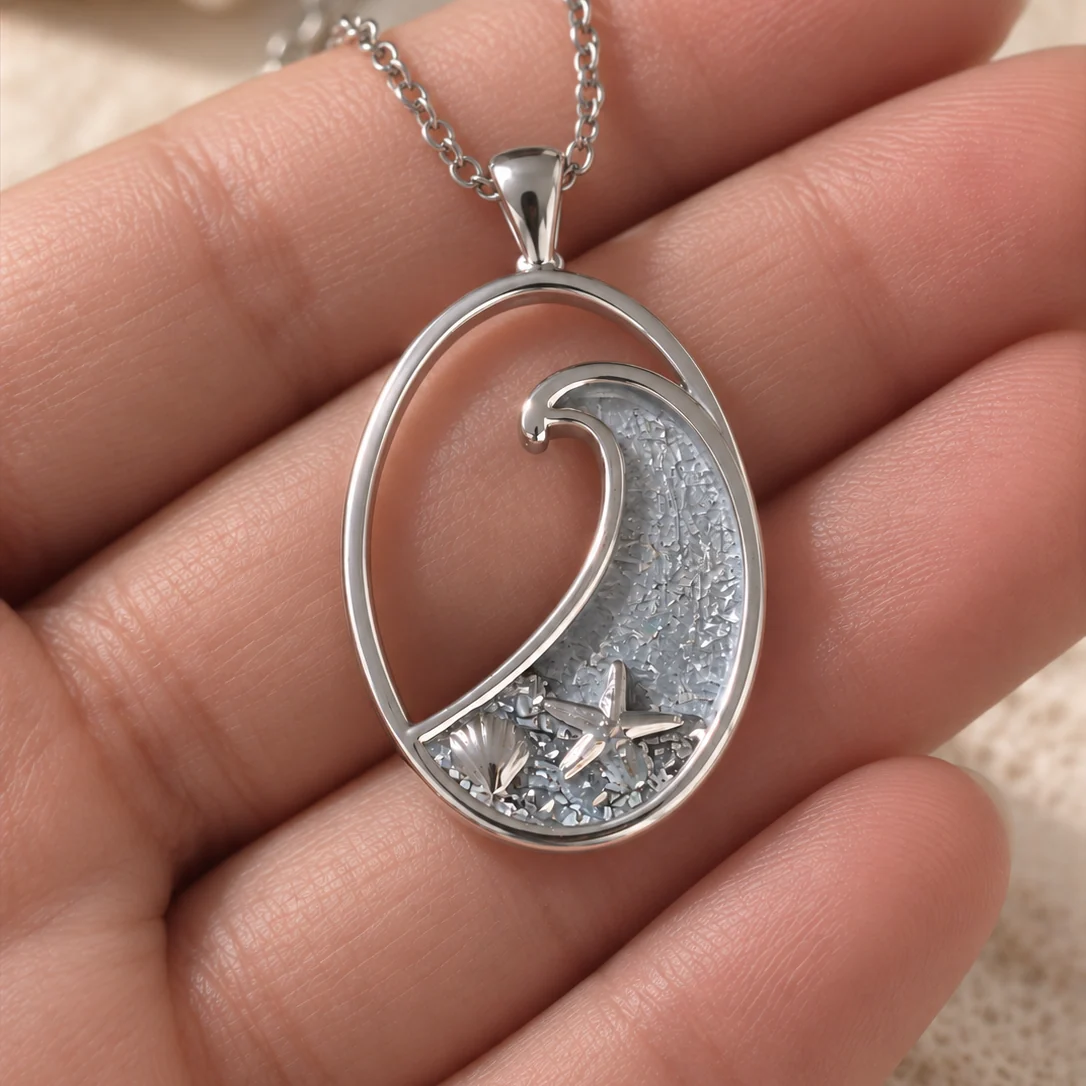 Ocean wave memorial pendant held in hand showing the wave, shell and starfish