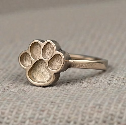 9ct gold paw print ring on fabric surface, angled view showing the paw print centrepiece and delicate band