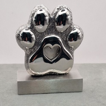 Chrome mirror-polished stainless steel paw print memorial ornament front view on stand showing heart-shaped resin recess in centre pad