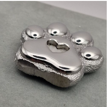Chrome mirror-polished stainless steel paw print memorial ornament top view showing domed toe beans and heart recess detail