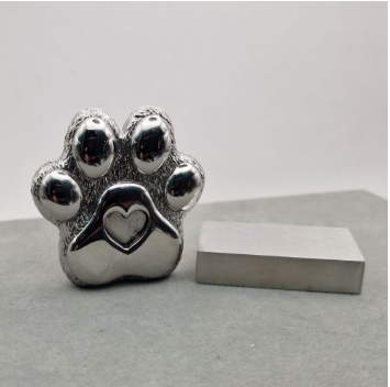 Chrome mirror-polished stainless steel paw print memorial ornament shown with brushed steel rectangular stand alongside