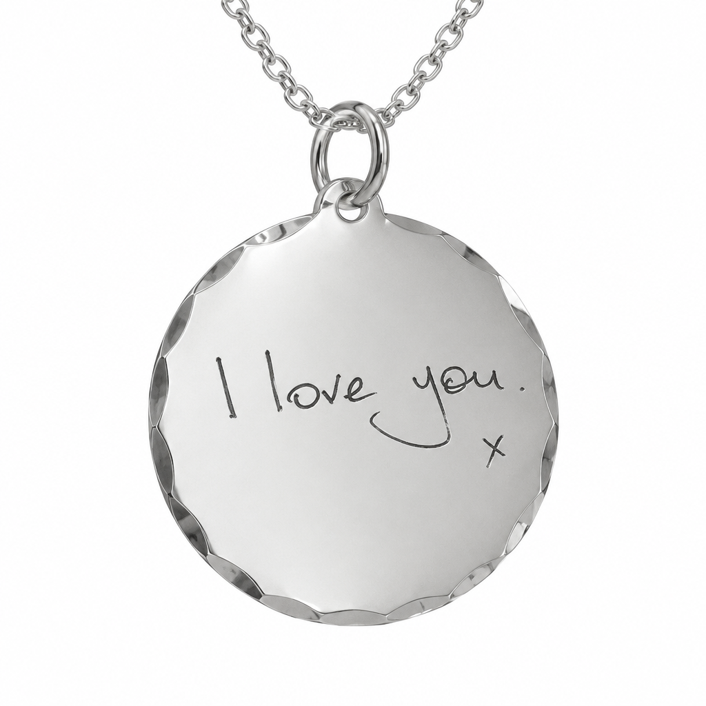 Illustrative handwriting engraving on scalloped sterling silver disc pendant and chain, white background