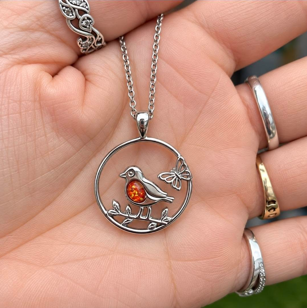 Robin and butterfly memorial pendant with orange opal resin in the robin's chest, held in hand