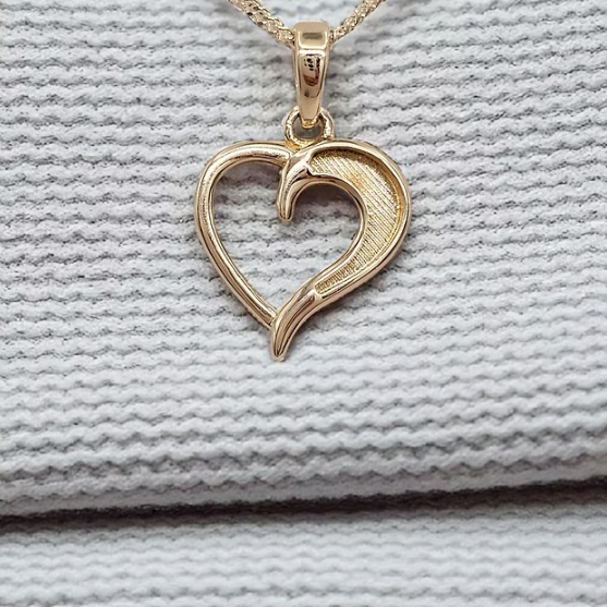 9ct yellow gold hollow heart pendant on gold chain on white knit fabric
