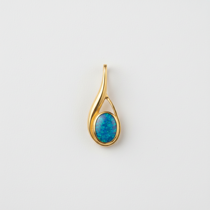 Hand holding 9ct gold teardrop swirl memorial pendant showing true scale – 29x11mm overall