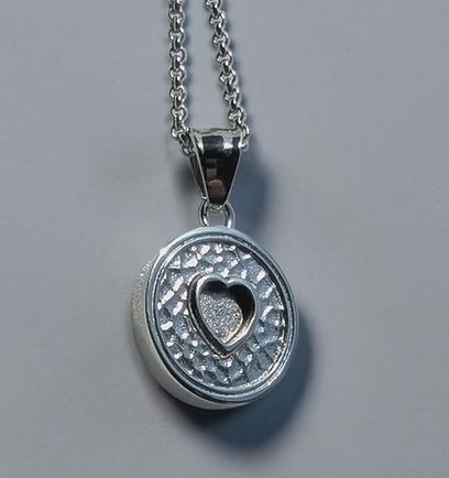 316L stainless steel eternal embrace pendant necklace showing round textured disc with raised heart bezel in centre on fine rolo chain