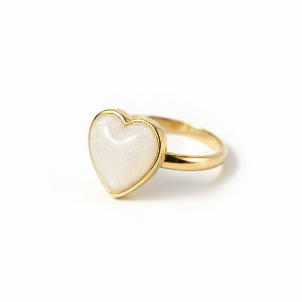 Gold heart-shaped ring with a white stone on a beige background