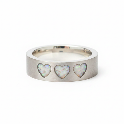 925 sterling silver three hearts memorial band ring with white pearl opal and mica shimmer in recessed heart settings on white background